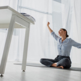 stock-photo-young-businesswoman-stretching-hands-practicing-yoga-lotus-position-mat-office